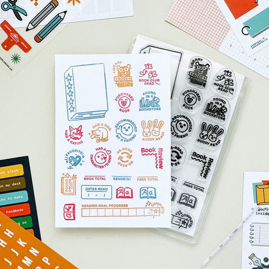 Set of colorful stamps and stamping plates on a light surface with stationery items.